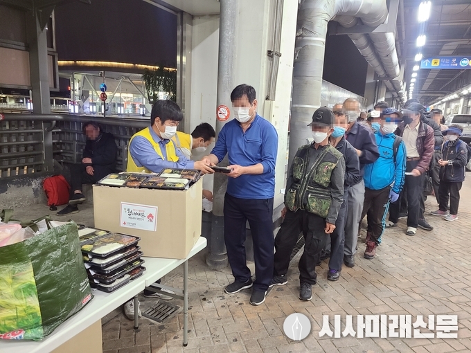봉사자들이 노숙인에게 도시락을 나눠주고 있다.
