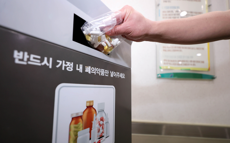 한 시민이 알약을 모은 비닐을 폐의약품 수거함에 버리고 있는 모습
