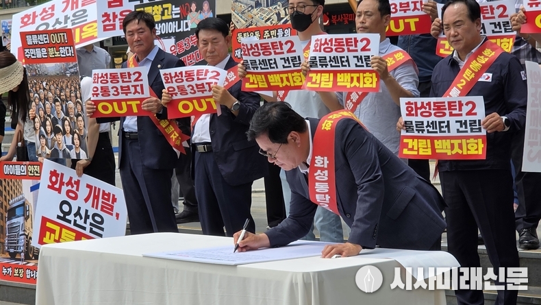 이상복 의장이 지난19일에 동탄호수공원 수변문화광장에서 진행된 동탄2 유통3부지 물류센터 건립계획 반대성명서 발표후 반대서명을 하고 있다.(사진=김은숙 기자)