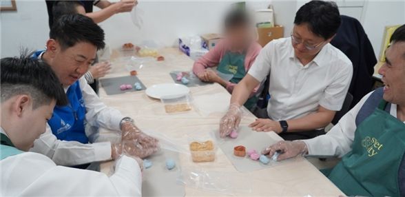 박지훈 신한은행 인천금융센터 지점장과 최진산 부지점장이 지난 1일 미추홀푸르내에서 거주 장애인들과 송편을 빚고 있다.