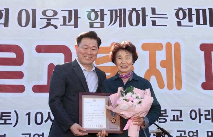 박승원 광명시장이 지난 1일 개봉교 아래 목감천 일대에서 열린 ‘제8회 광명2동 한마당 축제’에 참석해 어르신 환경봉사대 참여 어르신에게 시창 표창을 수여하고 기념사진을 촬영하고 있다.