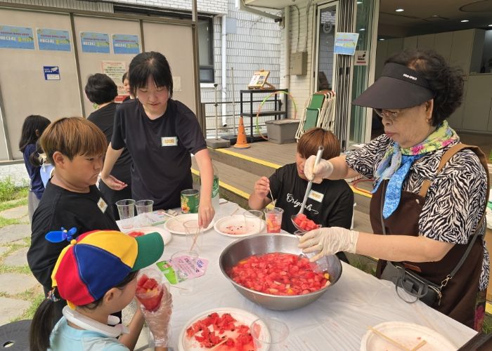 '우리마을 은빛 놀이터’프로그램에 참여한 어르신이 아이들에게 수박화채를 나눠주고 있다.